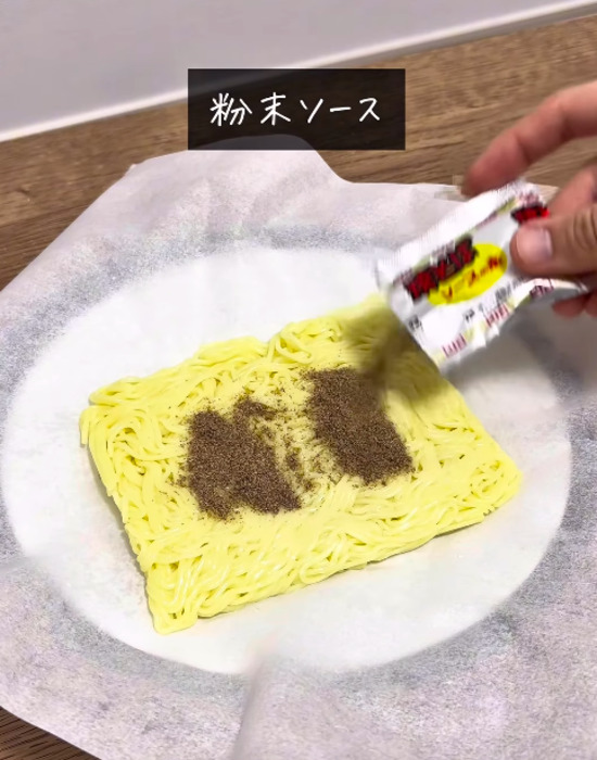 焼きそば麺に粉末ソースをかける様子