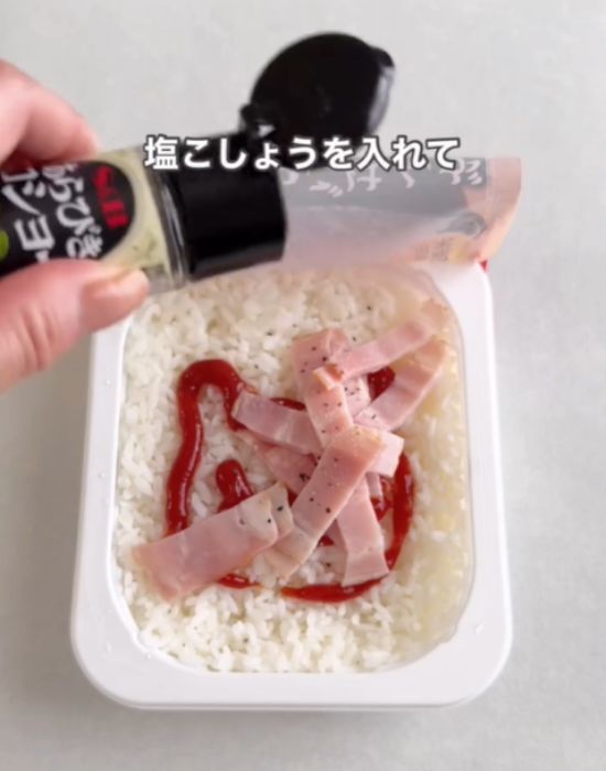 パックご飯にケチャップとベーコンと塩コショウを入れる様子