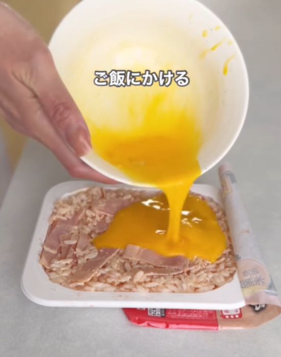パックご飯に溶き卵を流す様子