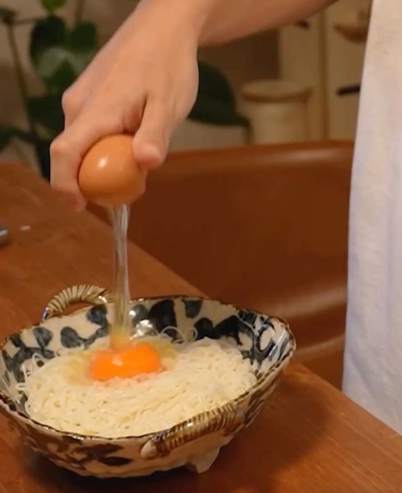 器に盛りつけたそうめんの上に卵を割り入れる様子
