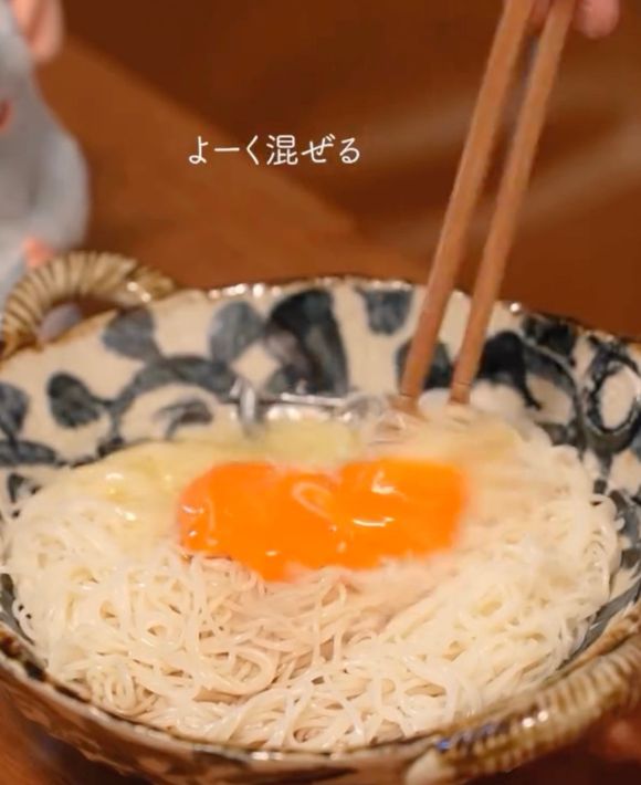 そうめんと卵と調味料がなじむように箸で混ぜる様子