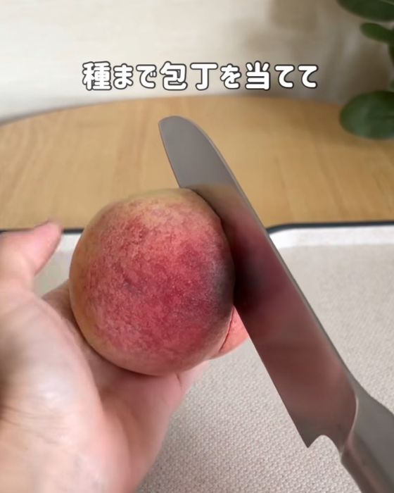 桃に包丁をあて種まで切り込みを入れる様子