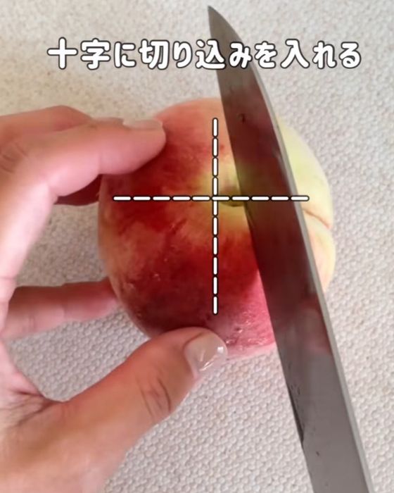 最初に入れた切込みに対して十字になるように桃に切り込みを入れようとしている様子