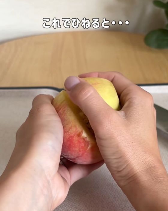 桃全体を手で覆ってひねる様子