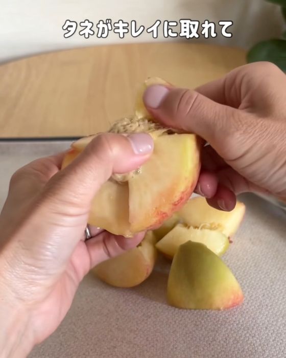 割った桃の種についた果肉を手ではがす様子