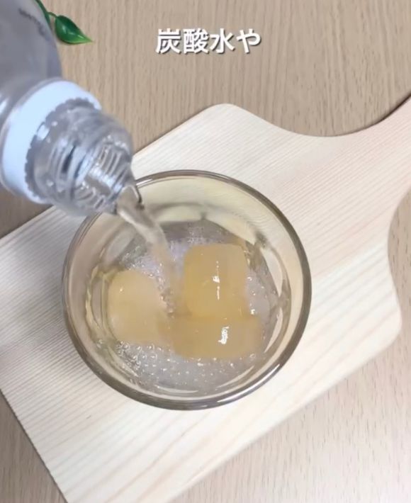 凍らせたグレープフルーツジュースのキューブをグラスに入れてその上から炭酸水を注ぐ様子