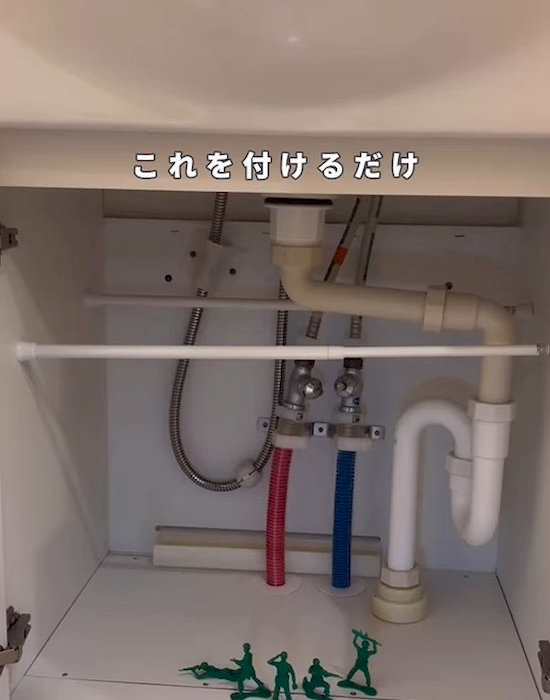 洗面台のシンク下につっぱり棒を取り付けている様子