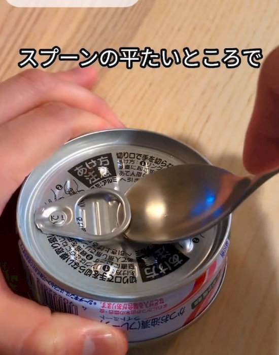 スプーンで缶詰を開けている様子