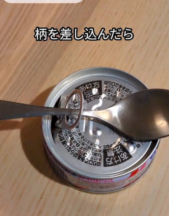 スプーンで缶詰を開けている様子