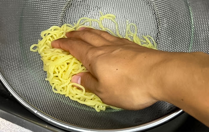 中華麺の水気を切っている写真