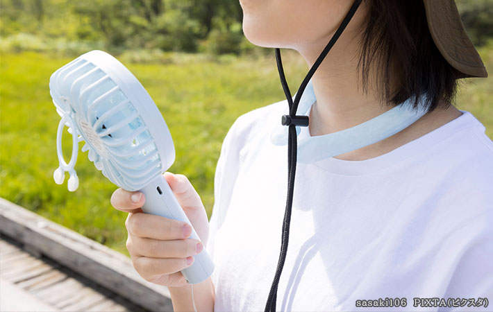携帯用扇風機を使う女性の写真