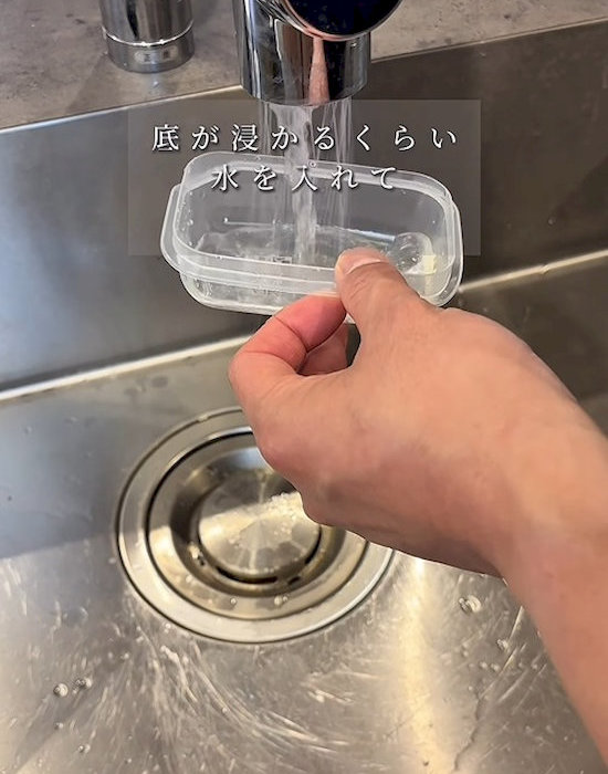 プラスチック製保存容器に水を入れる様子