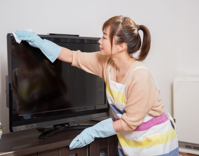 女性がテレビ画面を拭いている様子の写真