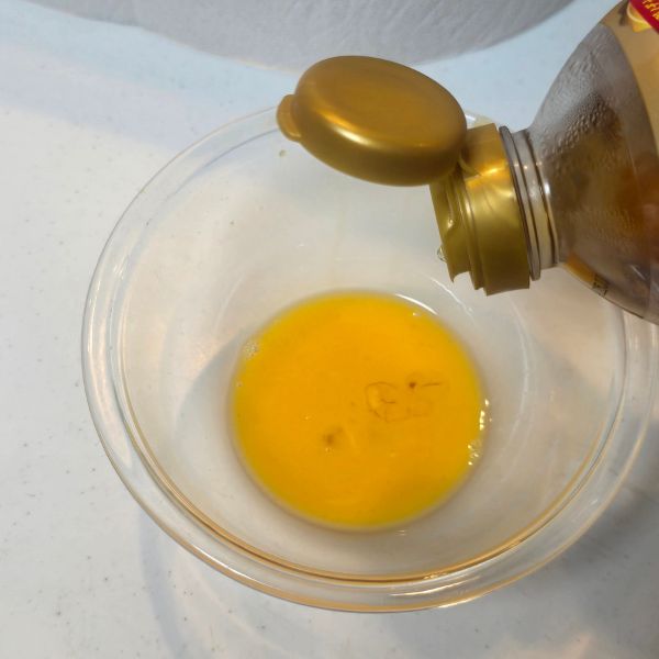 溶いた卵の入ったボウルに調味料を入れる様子
