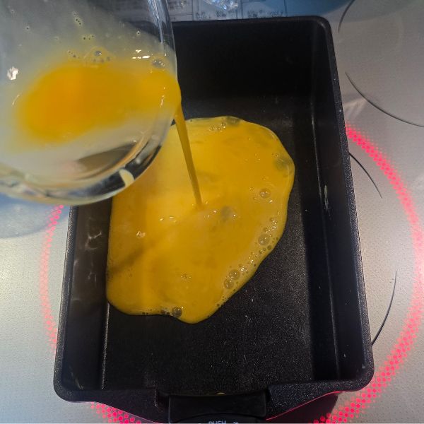 卵液をフライパンに流し入れる様子