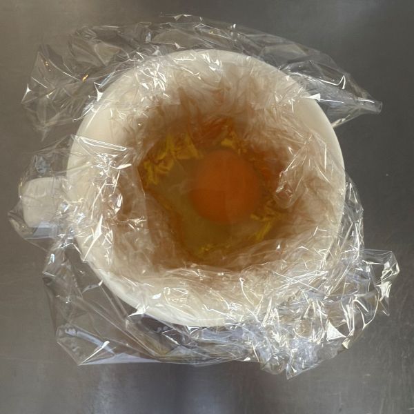 ラップを敷いたマグカップに卵と水と白だしを入れた様子