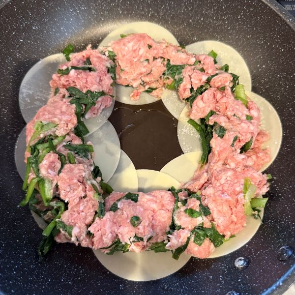 丸く並べた餃子の皮の上に餃子のタネをのせた様子