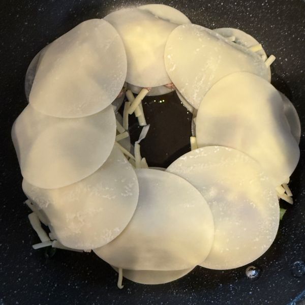 とろけるチーズをのせた餃子のタネの上にドーナツ状に餃子の皮をのせた様子