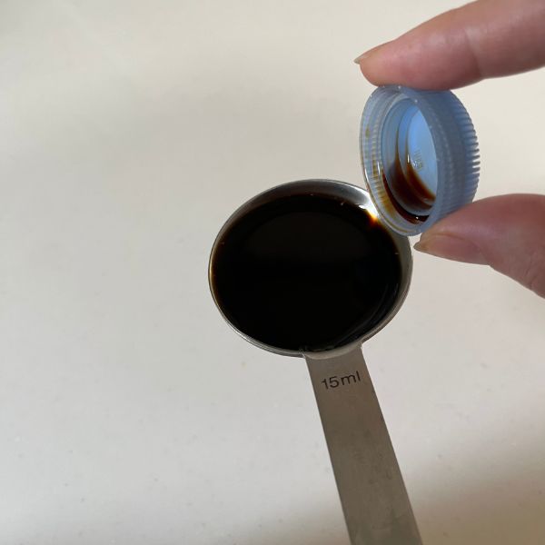 ペットボトルのキャップに醤油を入れて計量スプーンに移した様子