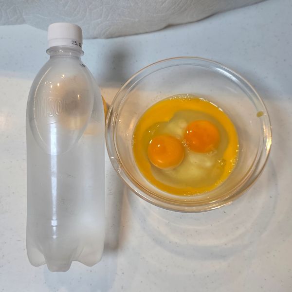 ボウルに割り入れた卵とペットボトルの炭酸水を並べた様子