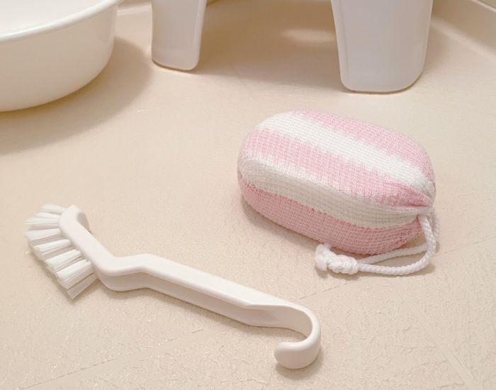 浴室の床に置かれたスポンジと掃除用ブラシの写真