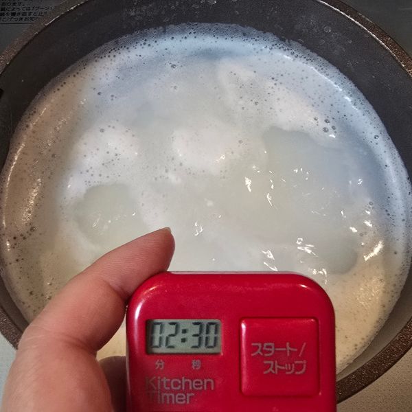 キッチンタイマーを手に持って時間を計る様子