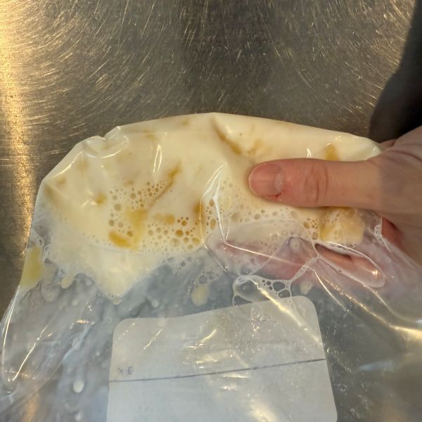 つぶしたバナナが入ったチャック付きの保存袋に牛乳を加えて外側からもむ様子