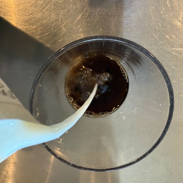 麦茶の入ったグラスに牛乳を注ぐ様子