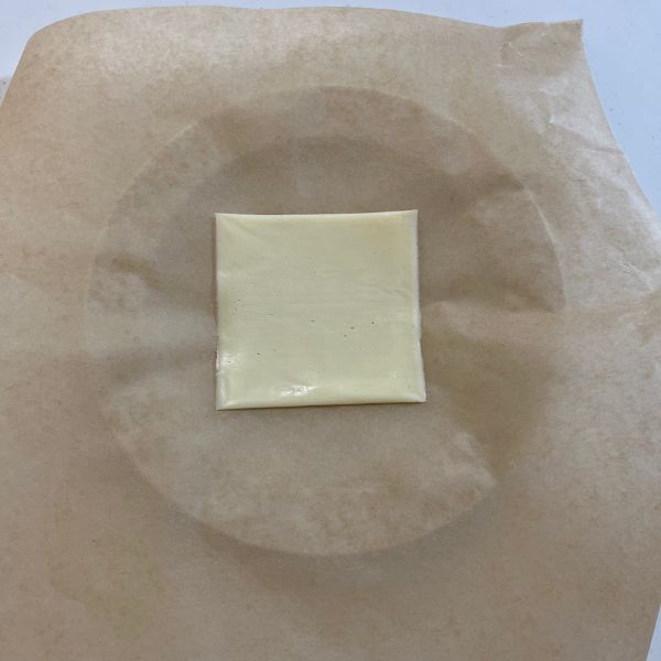 耐熱皿にクッキングシートを敷いてスライスチーズをのせた様子
