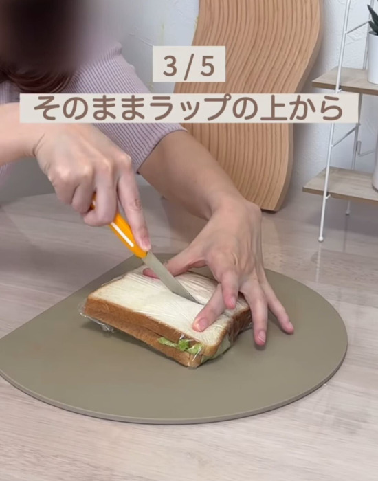 ラップを巻いたサンドイッチを包丁で切っている様子