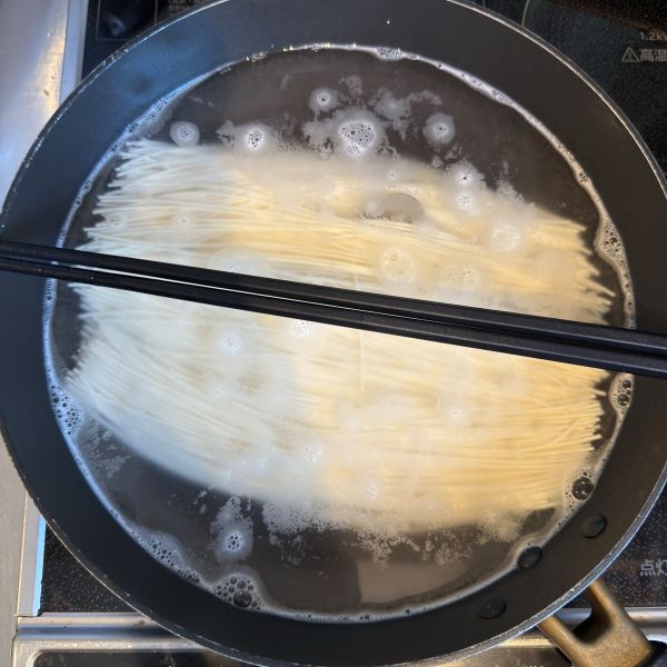 そうめんをゆでている鍋に菜箸をのせている様子