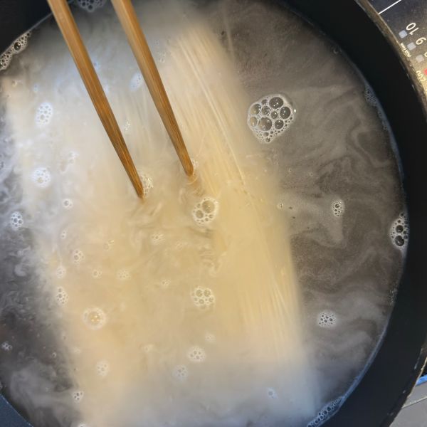 沸騰したお湯にそうめんを入れて菜箸で混ぜる様子