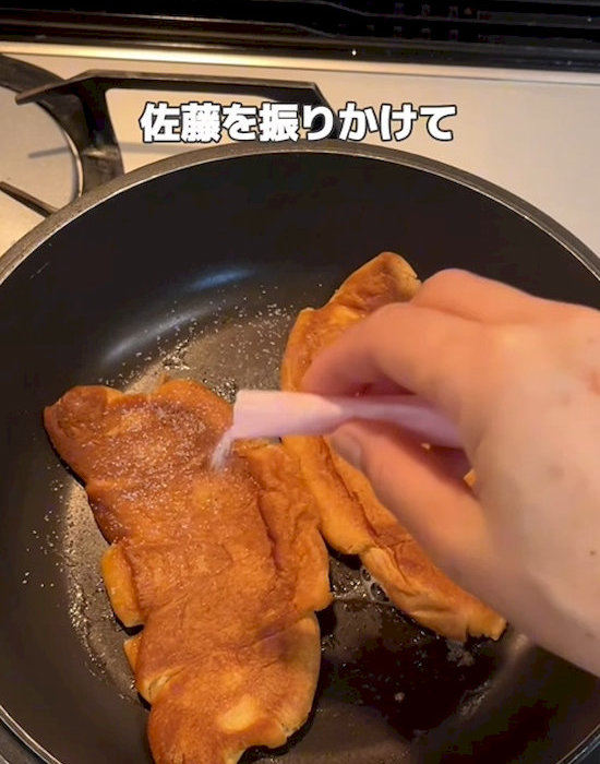 潰して焼いたクロワッサンに砂糖をかける様子