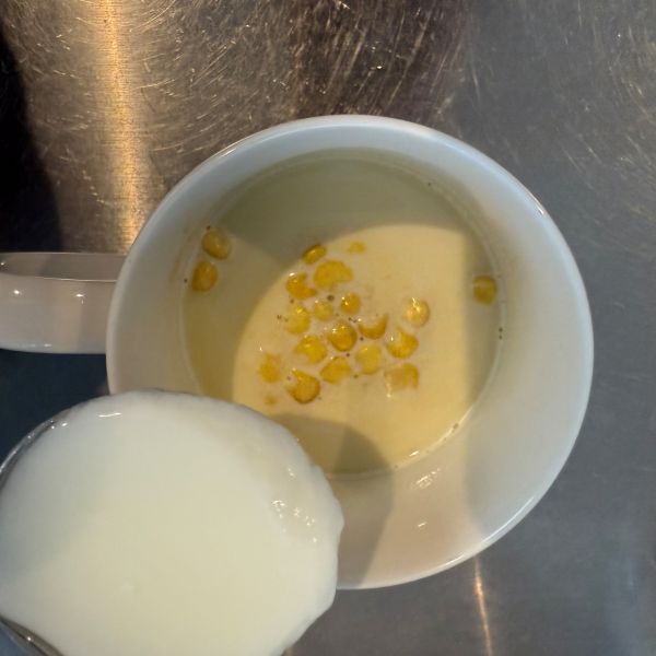 コーンスープの入ったマグカップにヨーグルトを入れる様子