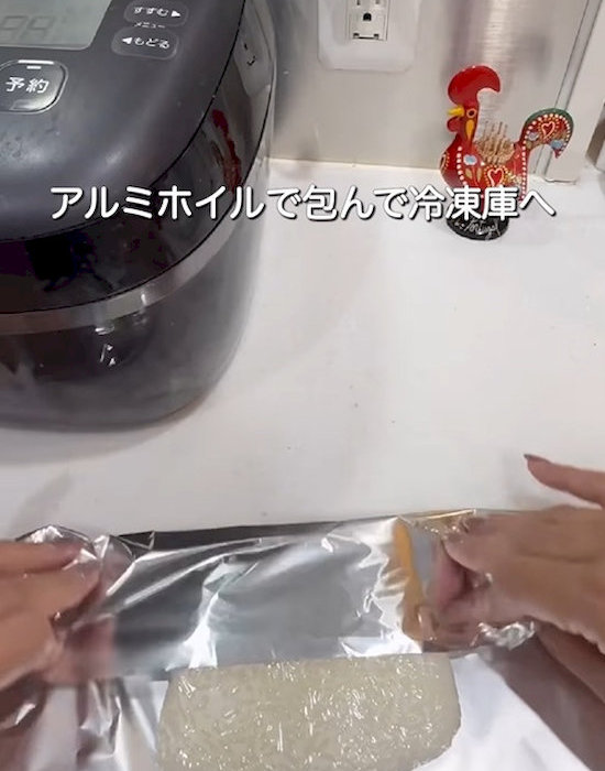 ラップで包んだご飯をアルミホイルで覆う様子