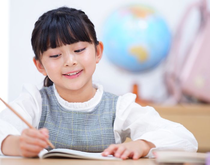 女児が鉛筆を持ってノートに書く様子