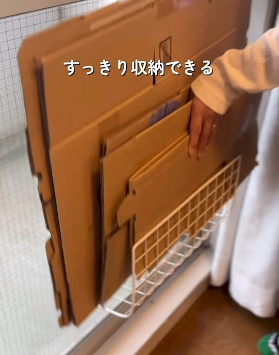 レバー式吸盤フックとワイヤーネットで作った収納にダンボールを入れている様子