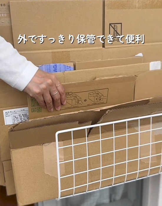 レバー式吸盤フックとワイヤーネットで作った収納にダンボールを入れている様子