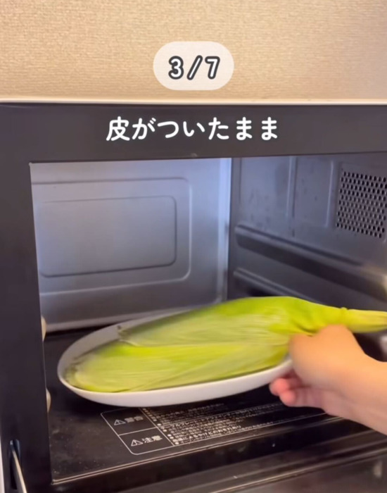 皮の付いたトウモロコシを電子レンジに入れている様子