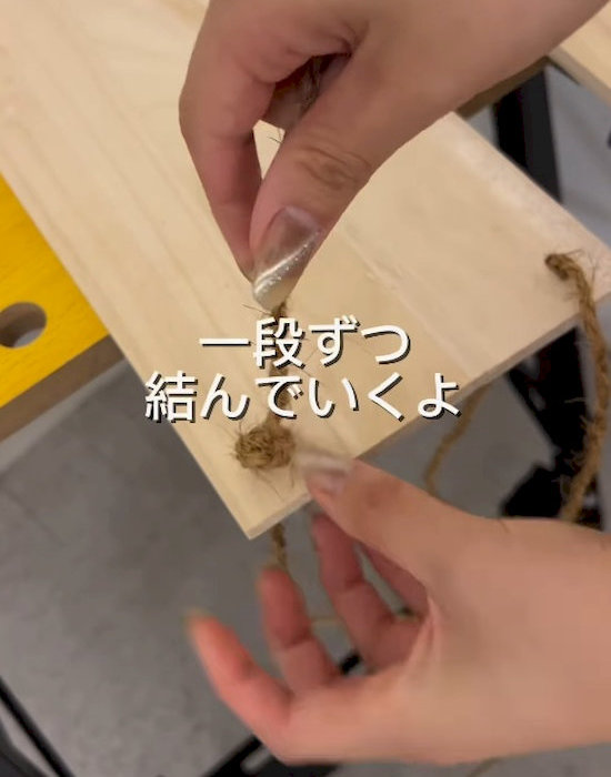 木の板の穴に紐を通す様子