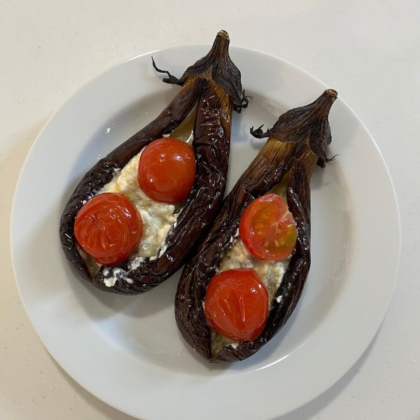 焼いたナスを皿に盛り付けて切れ目にローストしたミニトマトをトッピングした様子