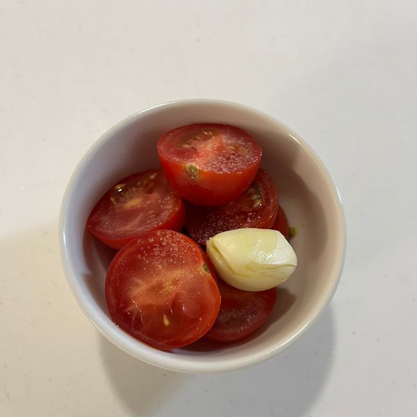 ココット皿に切ったミニトマトとつぶしたニンニクを入れた様子