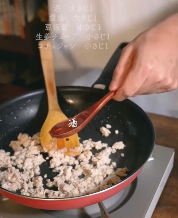 鶏ひき肉を炒めているフライパンに調味料を入れる様子