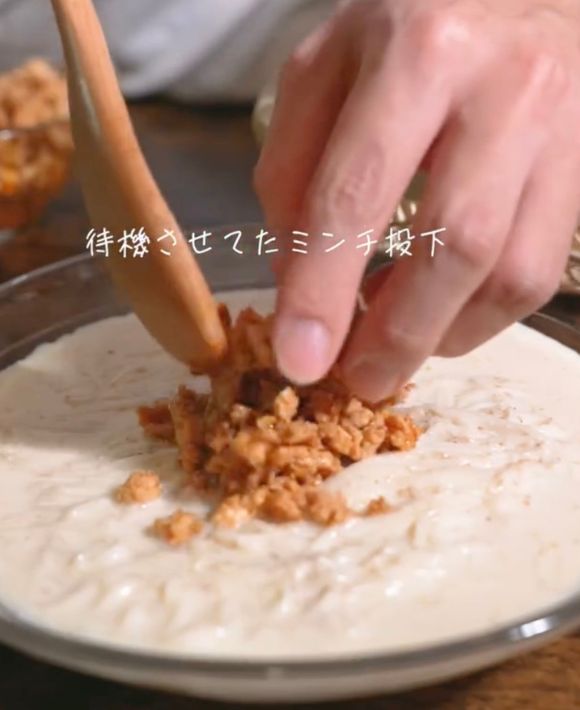 豆乳スープをかけたそうめんの上に炒めた鶏ひき肉をのせる様子