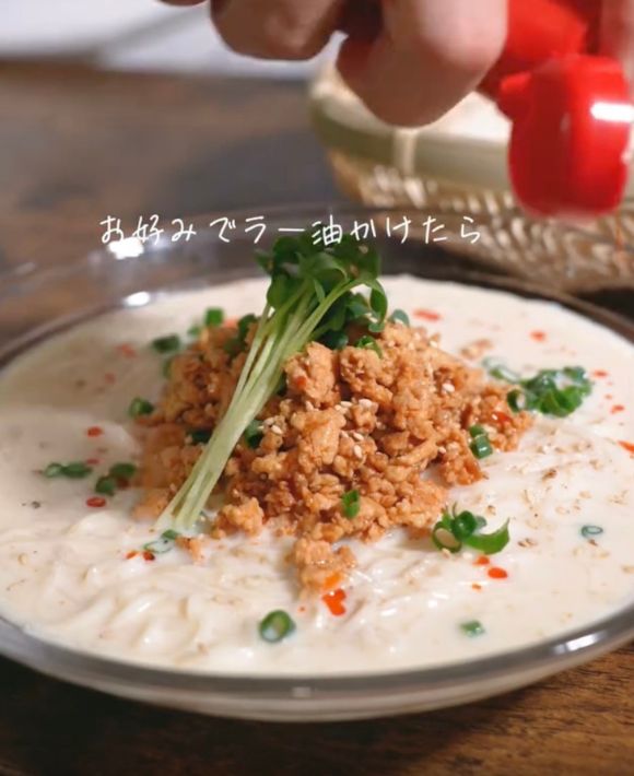 盛り付けた『冷やし豆乳担々そうめん』にラー油をかける様子