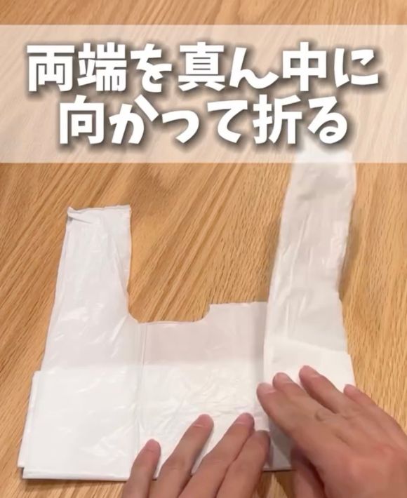 レジ袋の底側を折り畳んで裏返した状態で端を真ん中に向かって折る様子