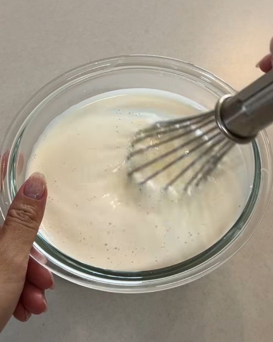 牛乳とチーズを入れたボウルを電子レンジで加熱した後泡だて器でかき混ぜる様子