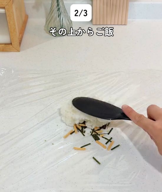 ラップの上に広げた『お茶づけ海苔』の上にご飯をのせる様子