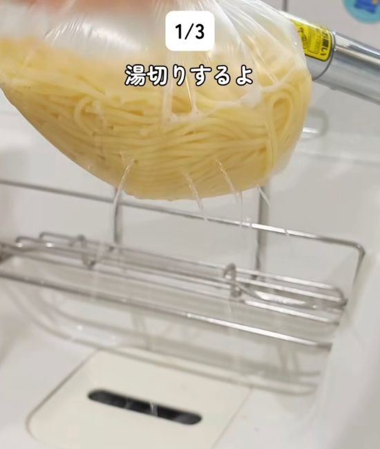 パスタと水を入れて加熱した『アイラップ』に穴を開けて湯切りする様子