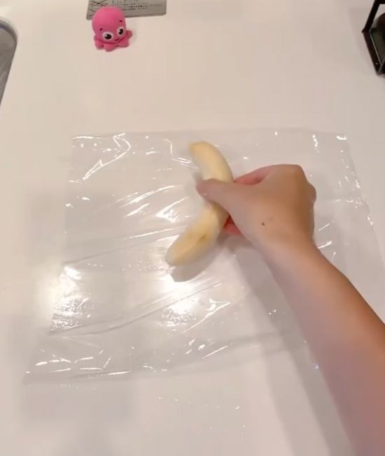皮をむいたバナナを作業台の上に広げたラップの上にのせる様子